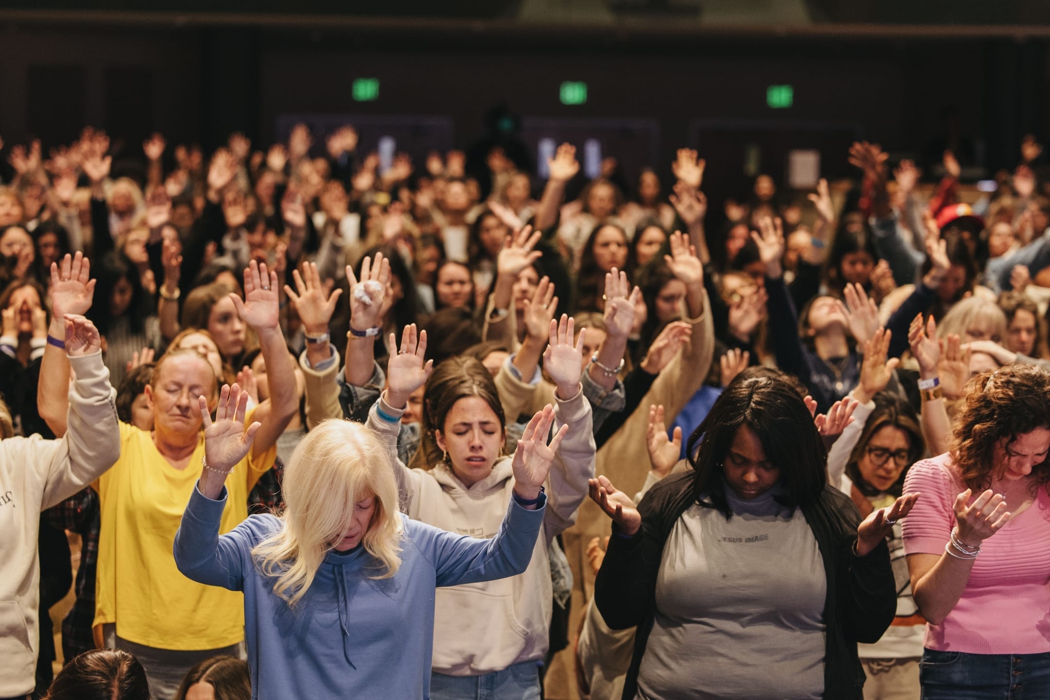 Woman's Conference attendees with arms and hands raised in worship